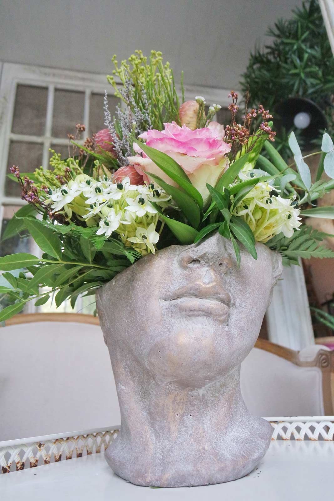 Arreglo de flor en maceta de busto griego